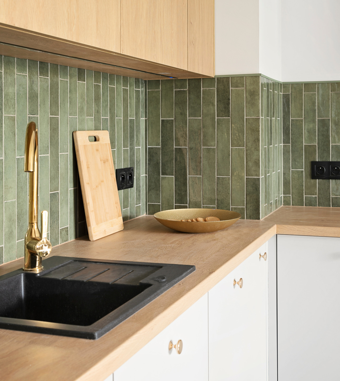 A kitchen with a wood-effect Signature Collections worktop, green tiled splashback and brass tap